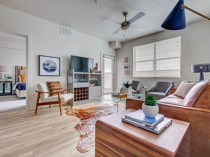 A living room with a brown couch, a wooden coffee table, and a ceiling fan.