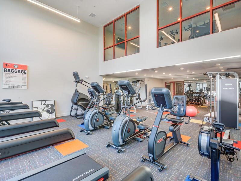 A gym with a variety of exercise equipment including treadmills, stationary bikes, and weight machines.