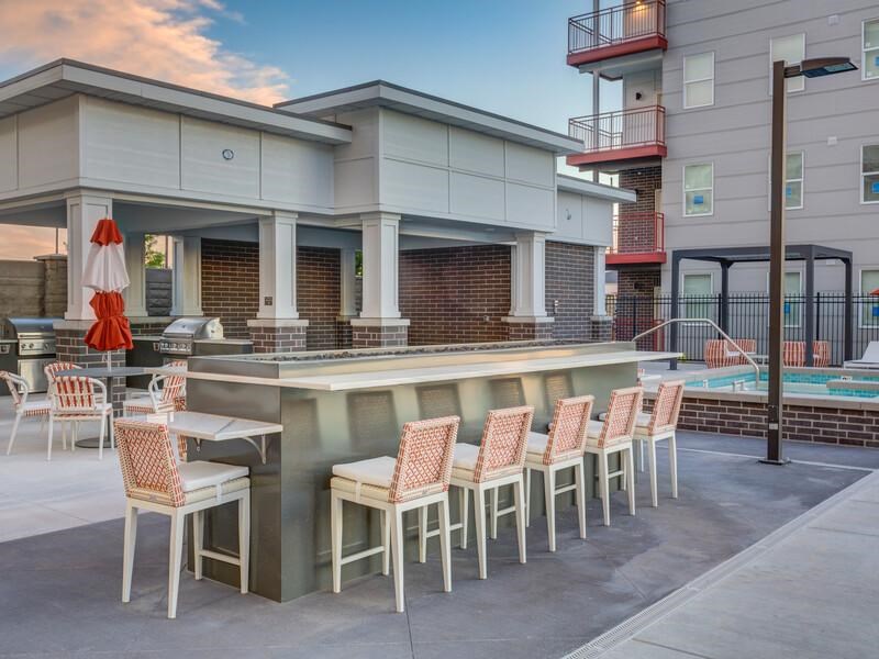 A patio with a bar and chairs is set up outside a building.