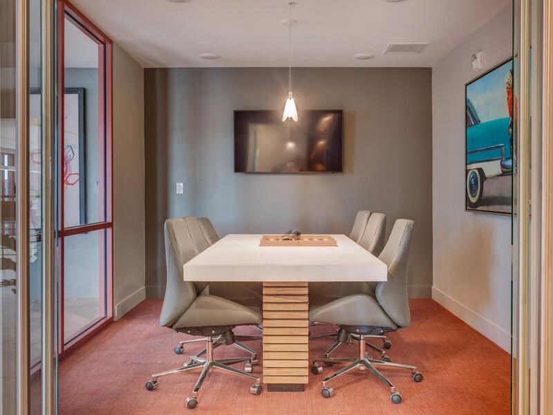 A conference room with a white table and grey chairs.