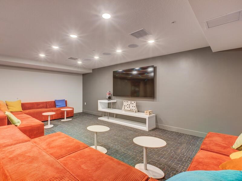 A room with orange and white furniture and a flat screen TV mounted on the wall.