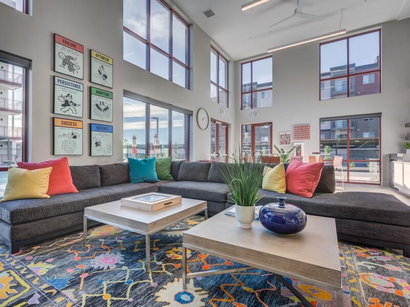 A living room with a grey couch, a coffee table, and a colorful rug.