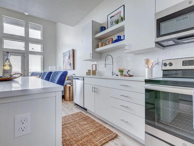 A modern kitchen with white cabinets and a blue cushion on the counter.