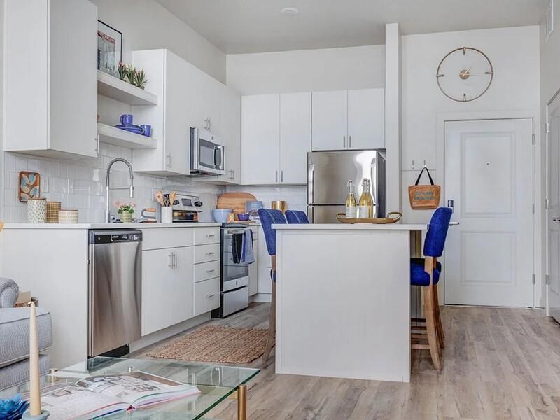 A kitchen with white cabinets and a glass table.