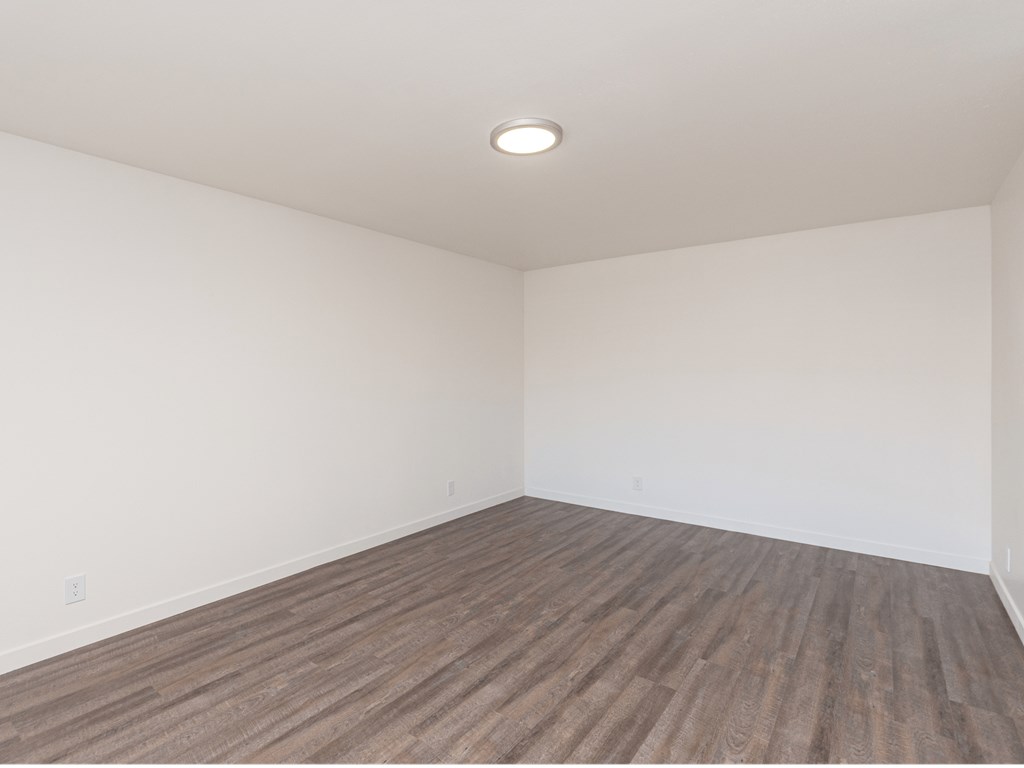an empty room with wood floors and white walls
