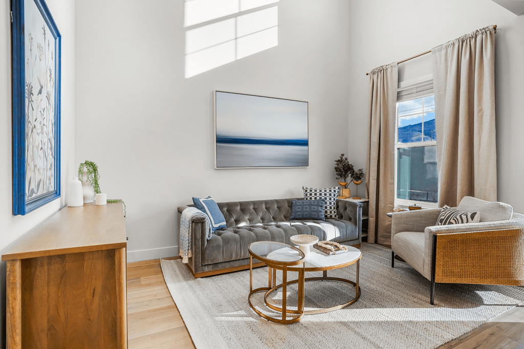 A living room with a grey sofa, a wooden side table, and a large painting on the wall.