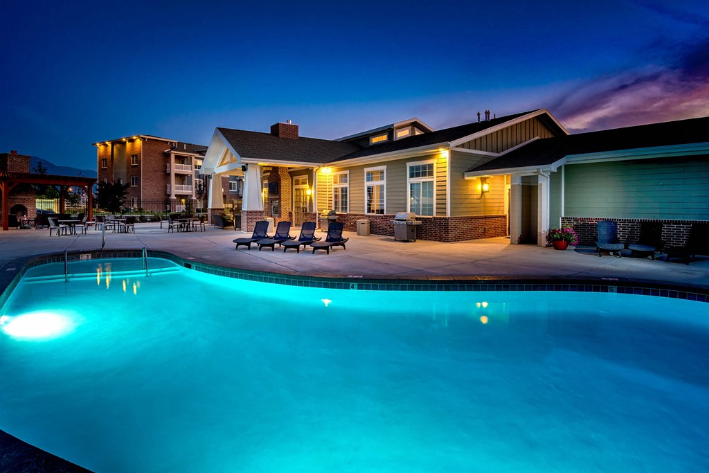 an evening view of the resort style swimming pool in front of the clubhouse at Outlook Apartments for rent in Springville and Provo, UT.