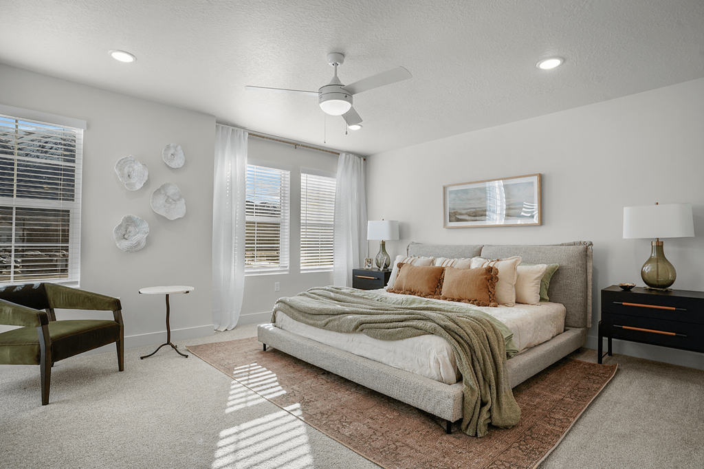 A bedroom with a bed, a chair, and a ceiling fan.