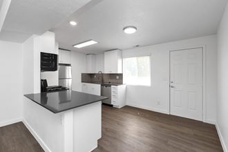 an empty kitchen with white cabinets and a black counter top
