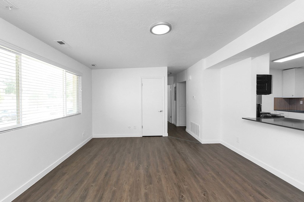 an empty living room with white walls and a window