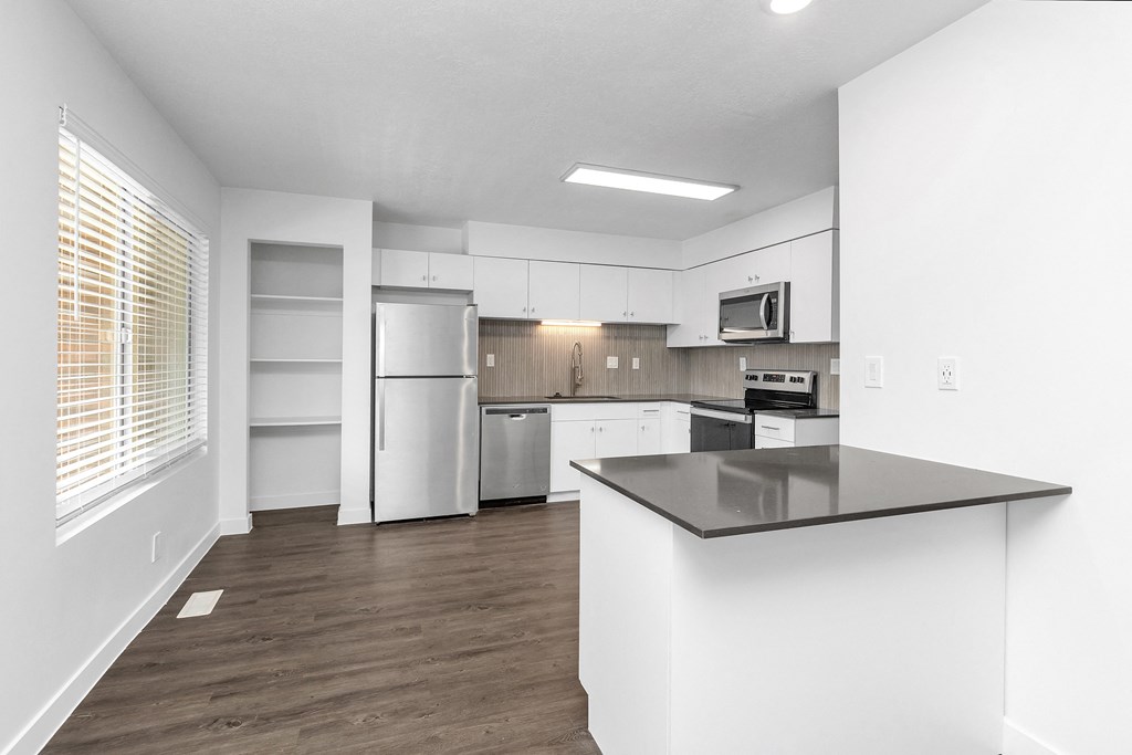 an empty kitchen with white cabinets and stainless steel appliances