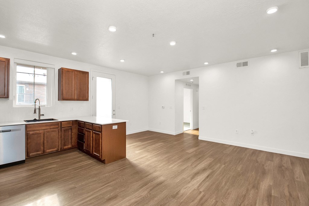 an empty kitchen and living room with wood floors and white walls