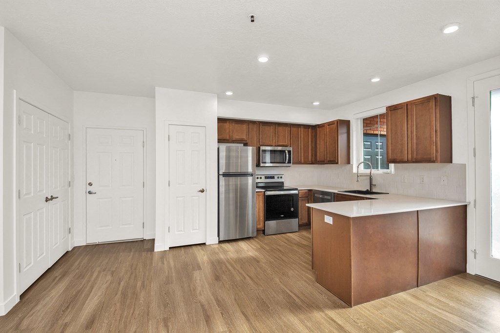 an empty kitchen with wooden floors and white walls and stainless steel appliances