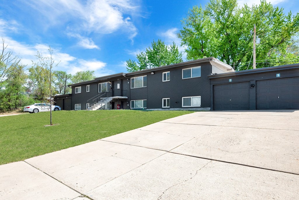 the front of an apartment building with a driveway and lawn