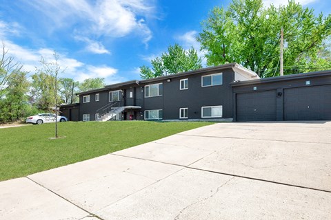 the front of an apartment building with a driveway and lawn