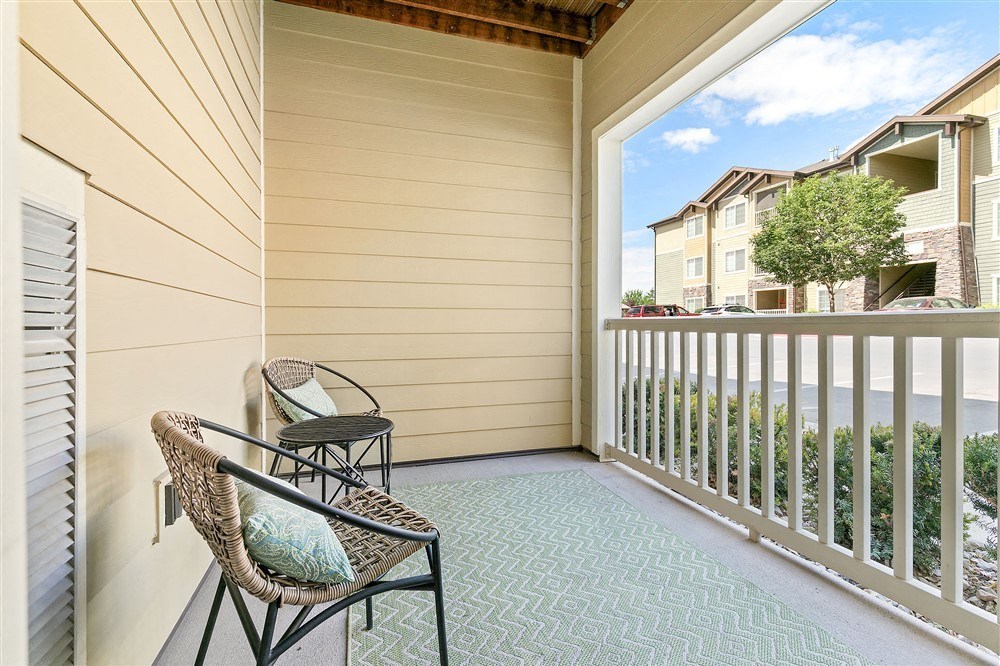 a balcony with two chairs and a view of a house at Aldara Apartments in Saratoga Springs, Utah