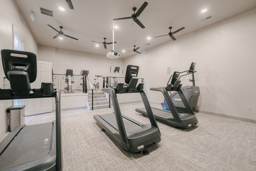 a gym with treadmills and other exercise equipment in a building with white walls at Aldara Apartments in Saratoga Springs, Utah