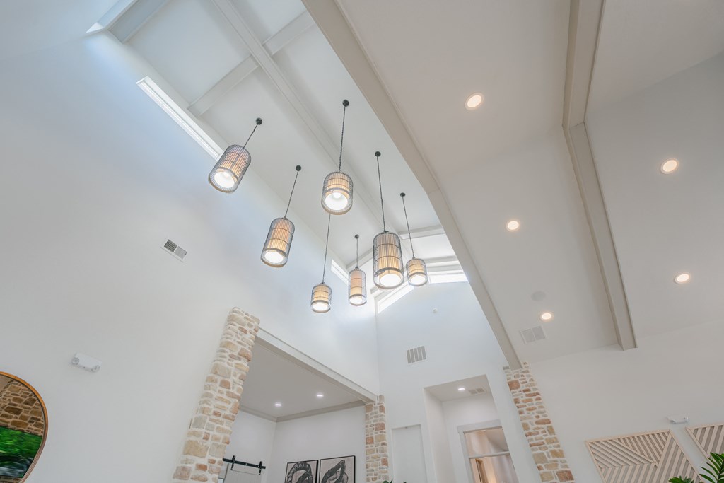 high ceilings and lights in a living room with a brick wall at Aldara Apartments in Saratoga Springs, Utah