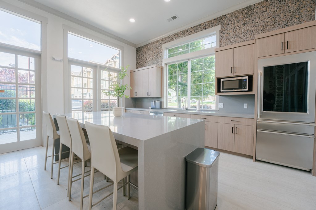 a large kitchen with a large island with white chairs at Aldara Apartments in Saratoga Springs, Utah
