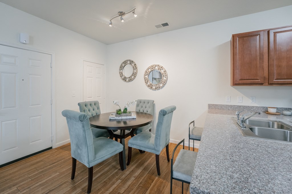 a dining room with a table and chairs and a kitchen with a sink at Aldara Apartments in Saratoga Springs, Utah