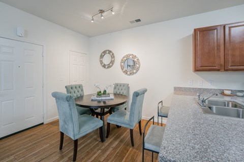 a dining room with a table and chairs and a kitchen with a sink
