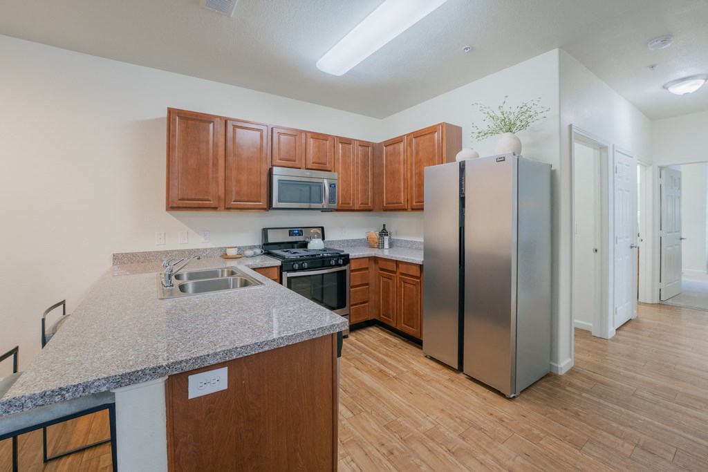 a kitchen with stainless steel appliances and a granite counter top at Aldara Apartments in Saratoga Springs, Utah
