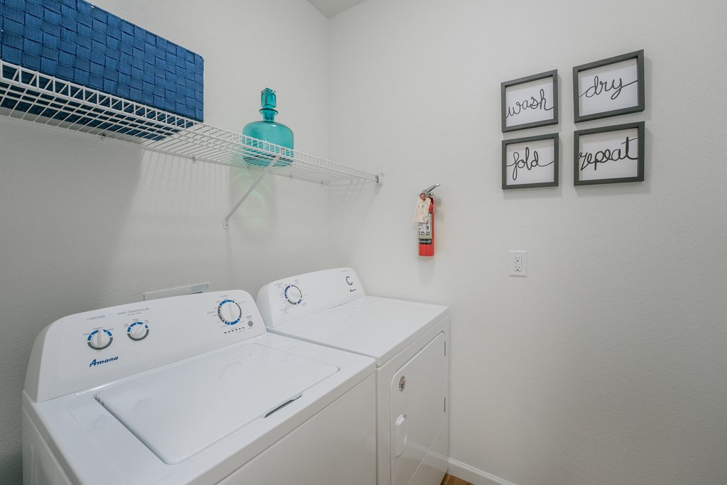 a washer and dryer in a laundry room with a shelf over the top at Aldara Apartments in Saratoga Springs, Utah