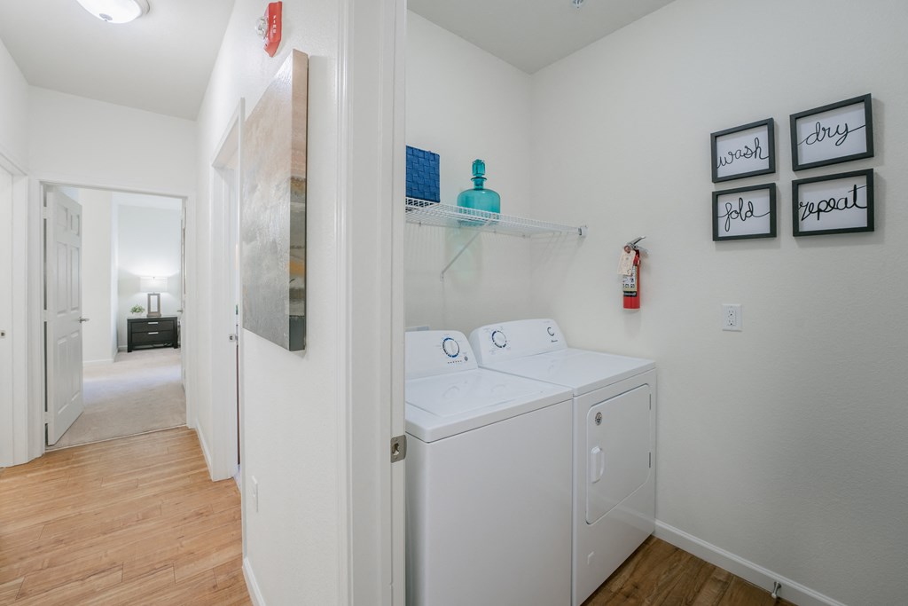 a laundry room with a washer and dryer and a hallway to a bathroom at Aldara Apartments in Saratoga Springs, Utah