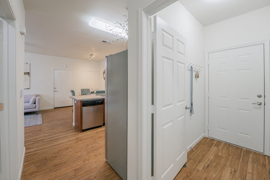 a renovated living room and kitchen with white walls and wood flooring at Aldara Apartments in Saratoga Springs, Utah