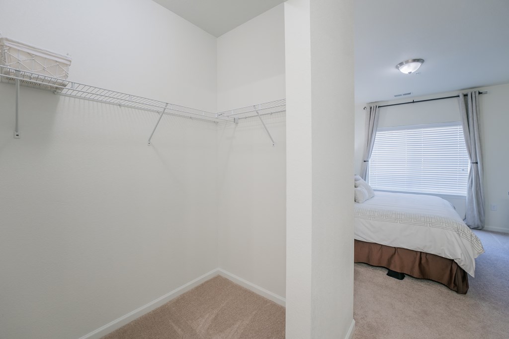 an empty bedroom with a bed and a closet with a window at Aldara Apartments in Saratoga Springs, Utah