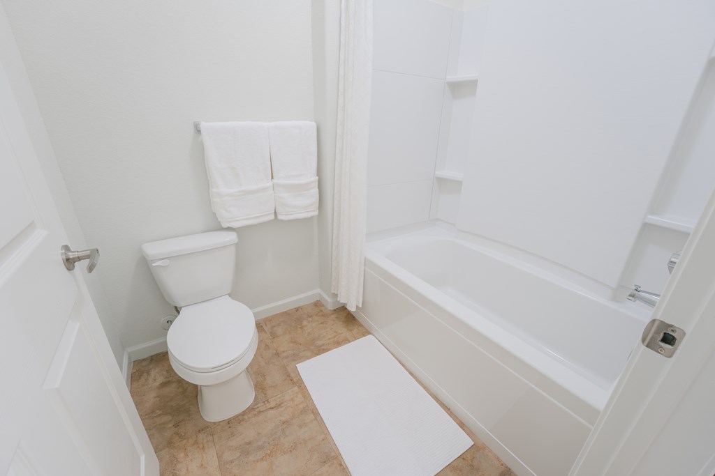 a white bathroom with a toilet and a tub at Aldara Apartments in Saratoga Springs, Utah