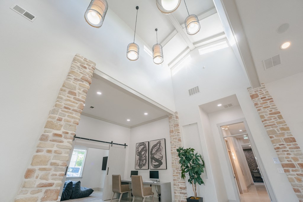 the living room and dining room in a modern home with exposed ceilings and brick columns at Aldara Apartments in Saratoga Springs, Utah