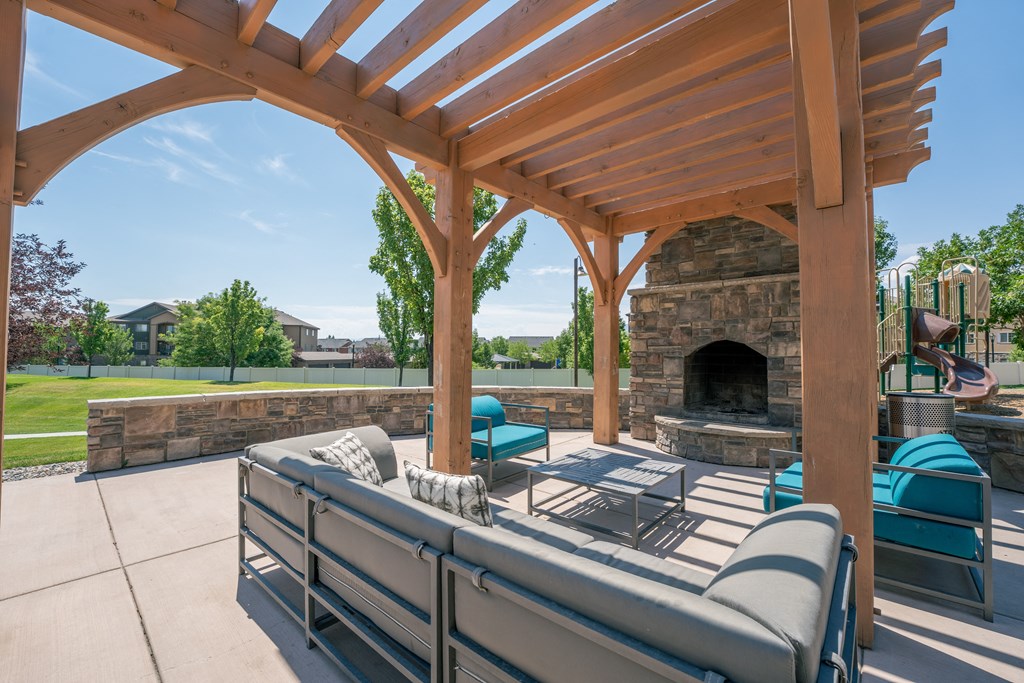the outdoor living area has a patio with a fireplace and couches at Aldara Apartments in Saratoga Springs, Utah