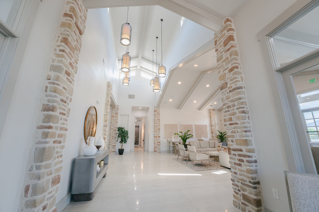 the lobby of a building with brick pillars and a reception area with chairs and tables at Aldara Apartments in Saratoga Springs, Utah