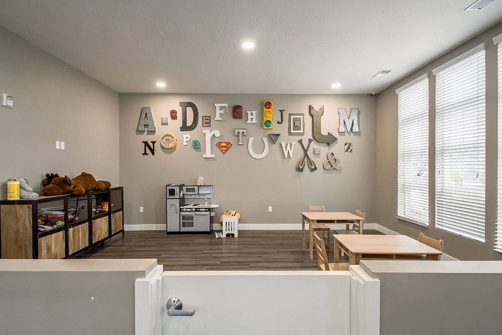 a room with two tables and two chairs and a wall with a alphabet sign on the wall