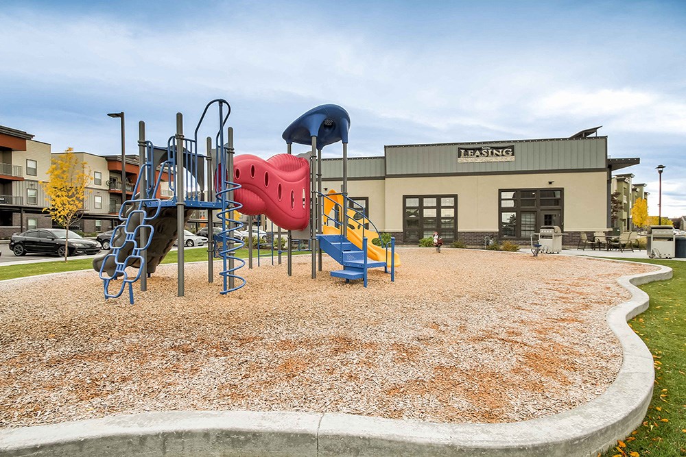 a playground in front of a building with a red and blue slide