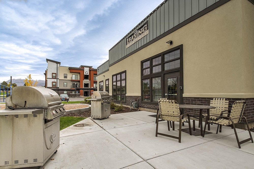 a patio with a grill and a table and chairs