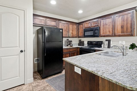 a kitchen with a granite counter top and a black refrigerator