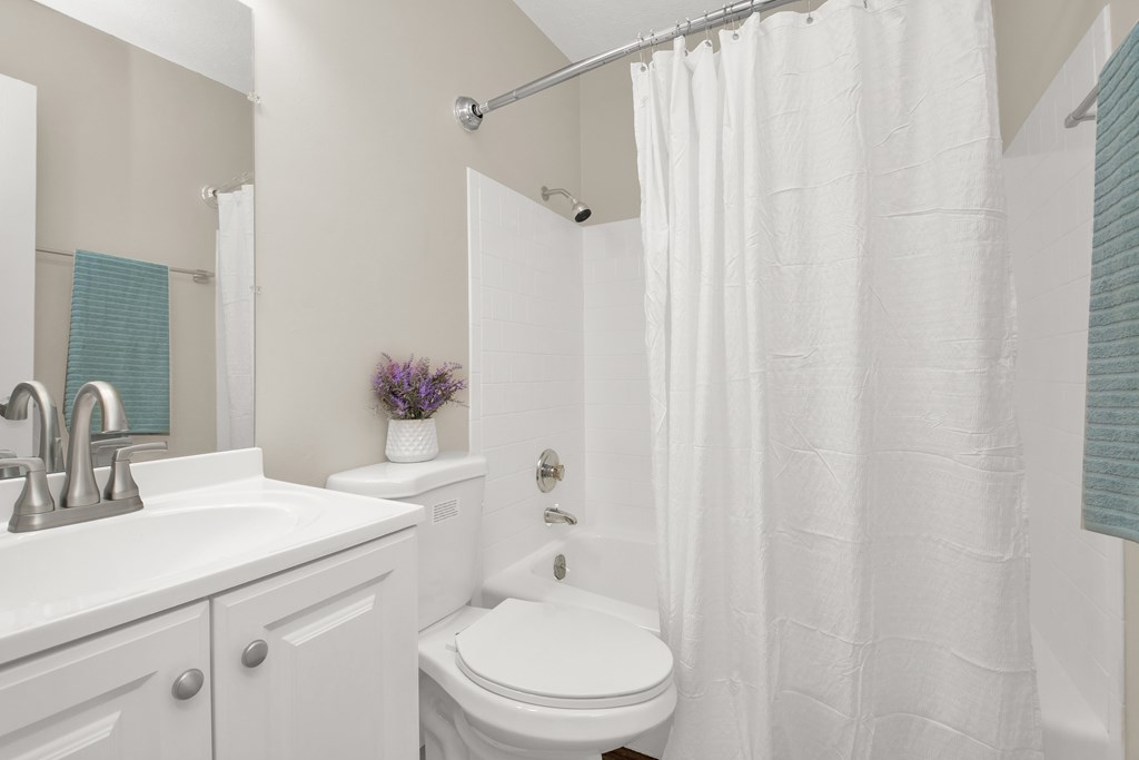 A white bathroom with a toilet, sink, and shower.