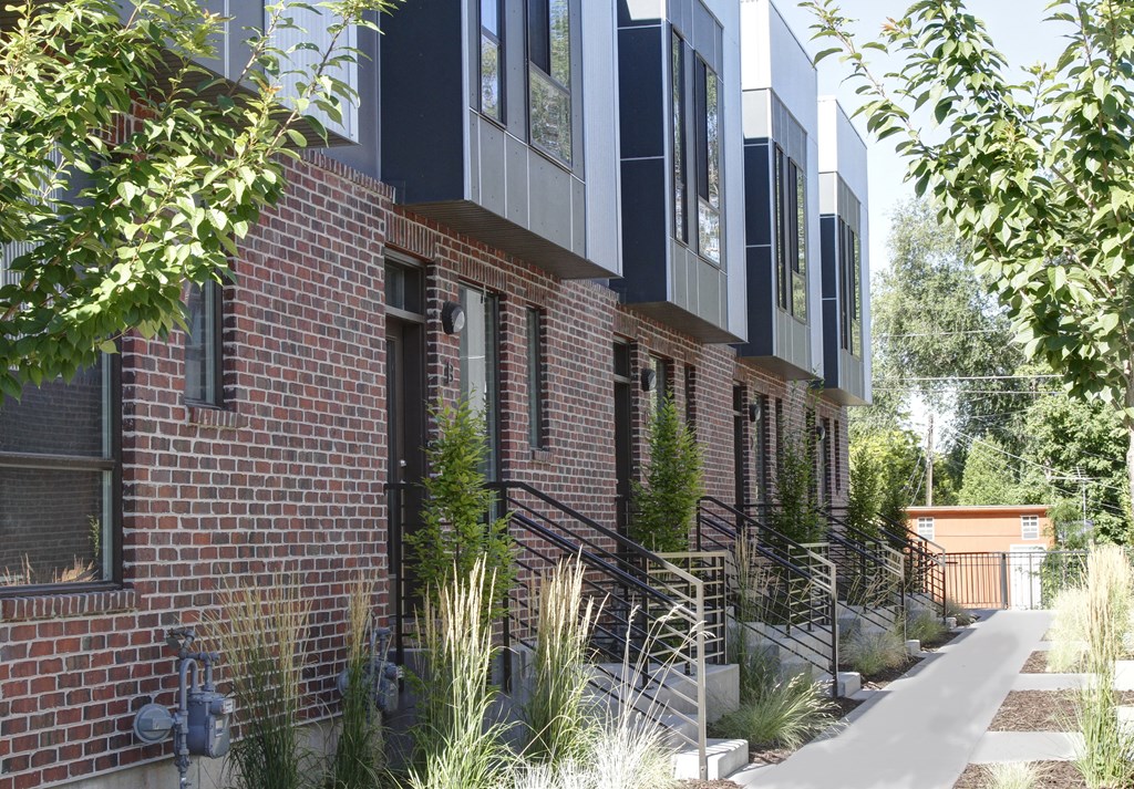 a red brick building with black windows and a sidewalk at BlueKoi Townhomes for rent in Salt Lake City, UT
