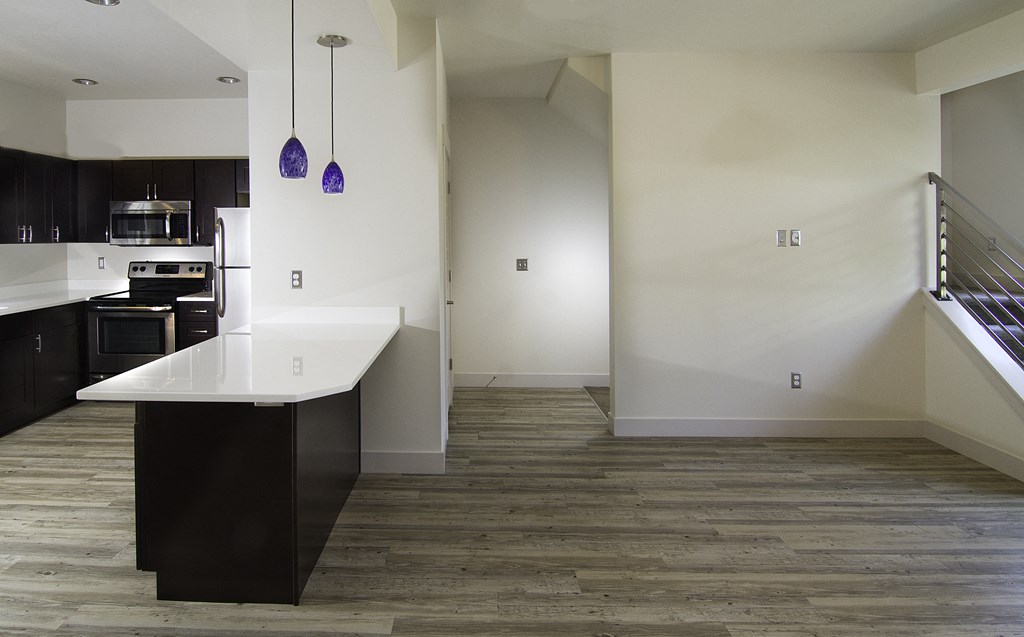 a view of a kitchen and living room with white walls and wood flooring at BlueKoi Townhomes for rent in Salt Lake City, UT