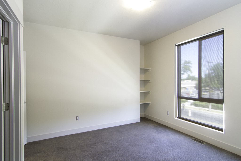an empty living room with a large window and white walls at BlueKoi Townhomes for rent in Salt Lake City, UT