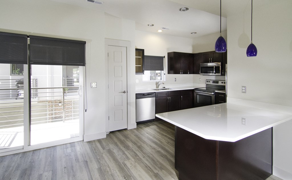 a kitchen with a white counter top and a sliding glass door at BlueKoi Townhomes for rent in Salt Lake City, UT