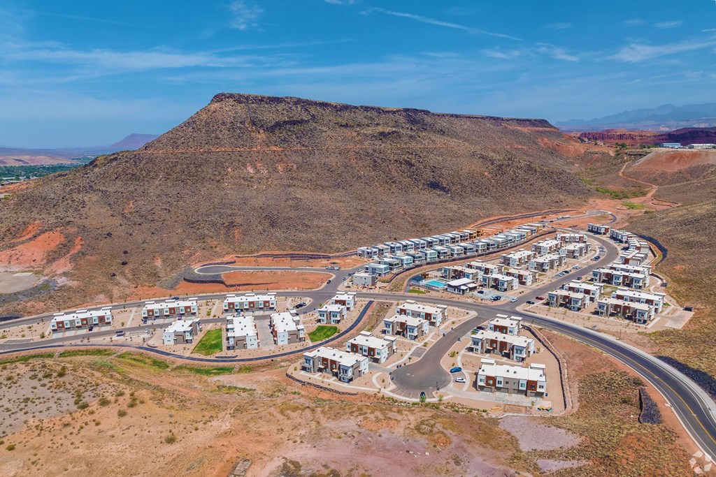 A housing development is situated on a hillside with a road curving around it.