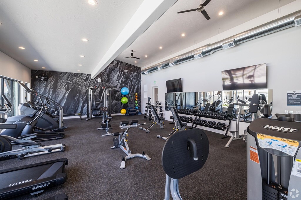 A gym with a variety of equipment including treadmills, weights, and exercise machines.