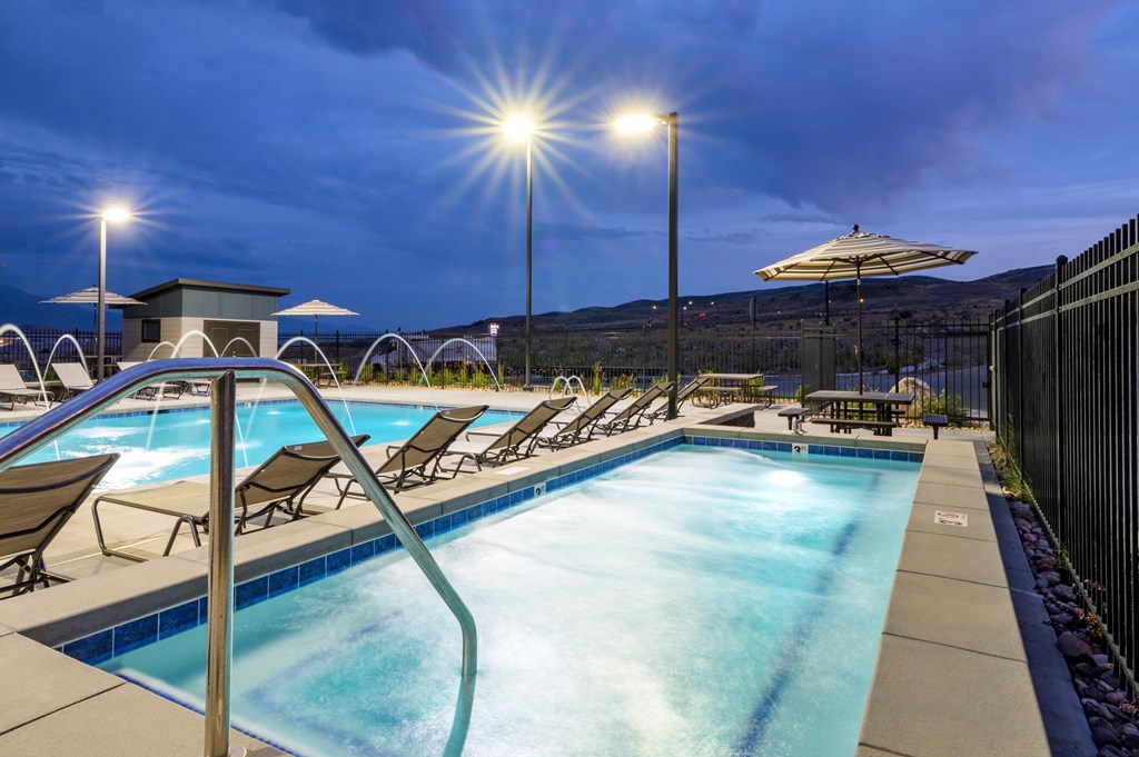 A swimming pool with sun loungers and a fence.