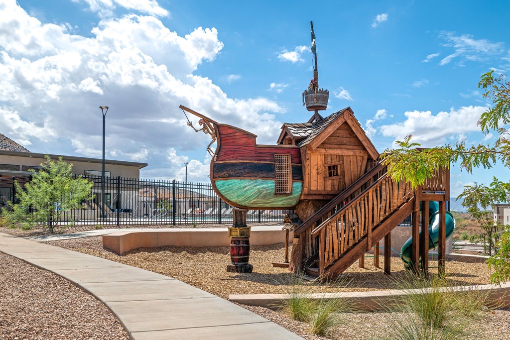 A playground with a wooden pirate ship structure and a green slide.