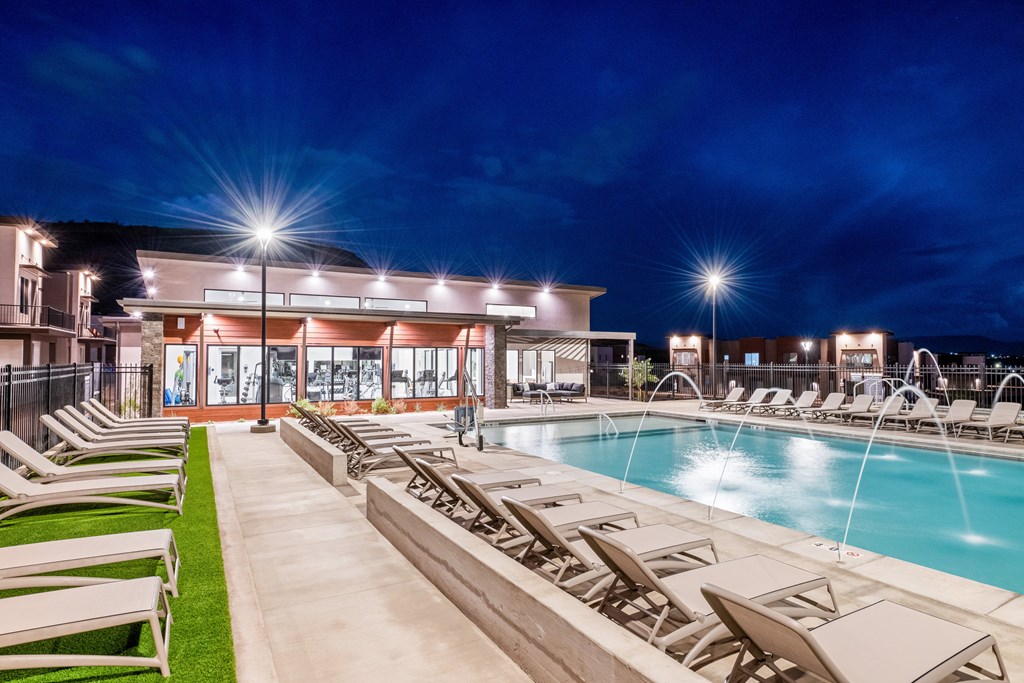 A poolside area with lounge chairs and a building in the background.