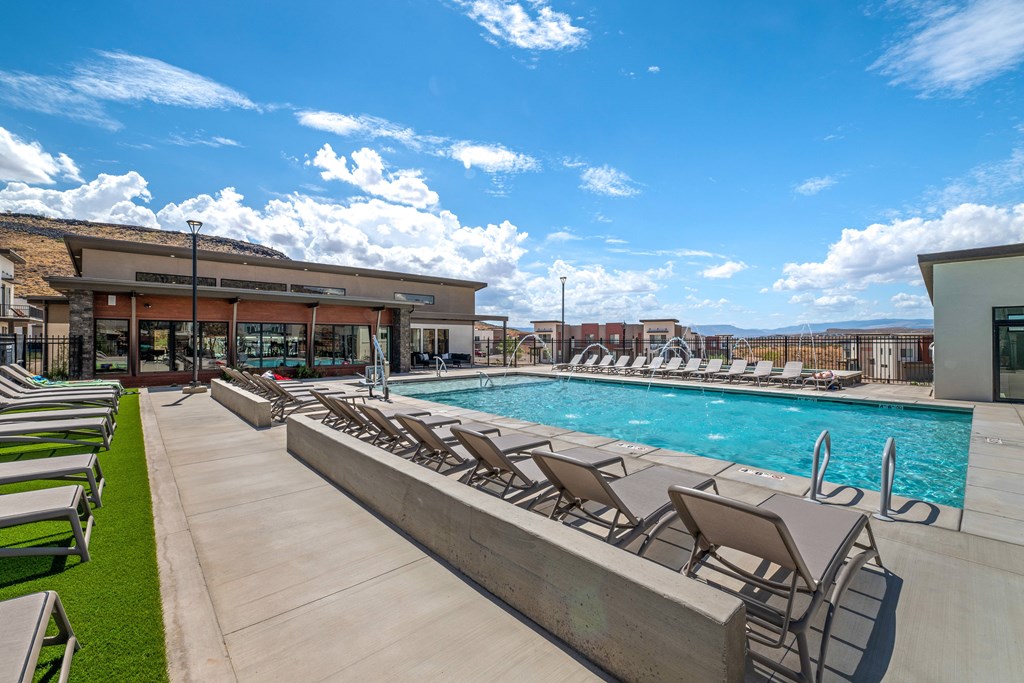 A pool with sun loungers and a building in the background.