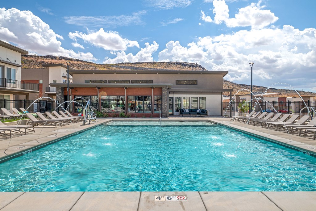 A large swimming pool with lounge chairs and a building in the background.
